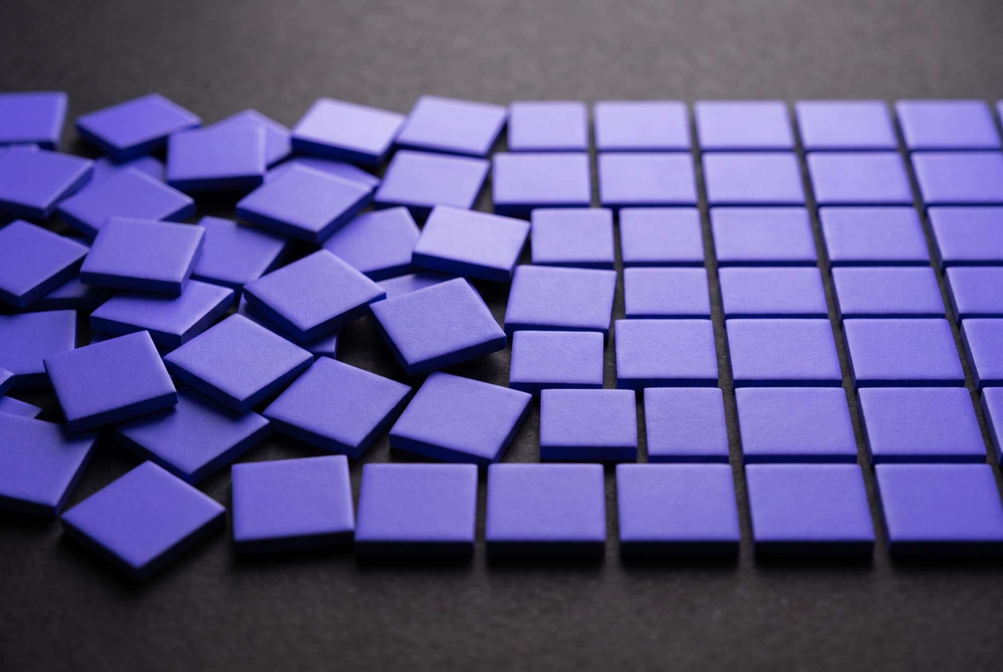 Blocos violeta sobre uma superfície escura, do caos à grade organizada